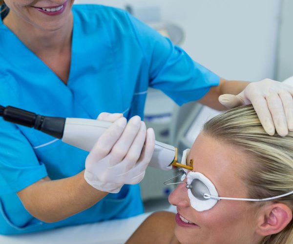 Woman receiving laser epilation treatment on her forehead at beauty salon